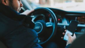 A man looking at his phone while sitting in a car