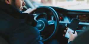 A man looking at his phone while sitting in a car