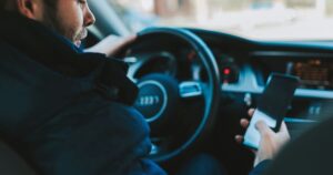 A man looking at his phone while sitting in a car