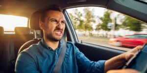 An angry looking man driving a car