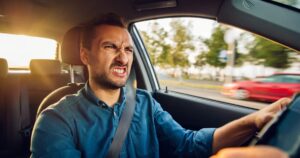 An angry looking man driving a car