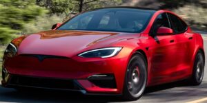 A red tesla parked under shady trees