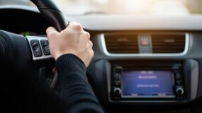 A close up on a man's hand on a steering wheel